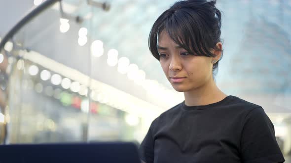 Portrait of Young Woman with Laptop on Background of Shopping Mall