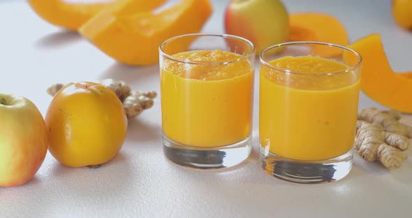 Pumpkin and Ginger Smoothie is Poured Into Glasses Against a Background of Fresh Vegetables and