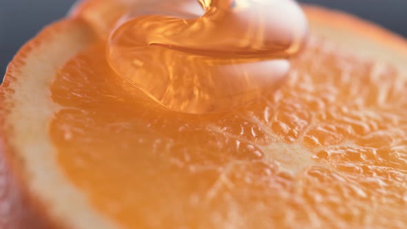 Thick honey dripping over cut orange. Slow Motion.