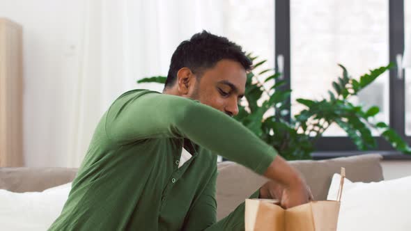 Smiling Indian Man Unpacking Takeaway Food at Home