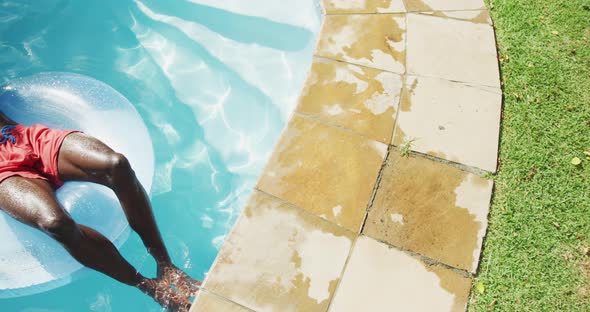 Handsome african american man lying on inflatable sunbathing in swimming pool