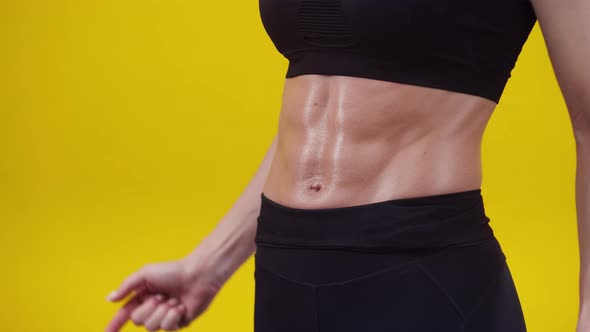 Woman Points Fingers at a Muscular Belly in the Studio Closeup