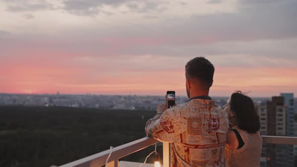 Man Photographing Sunset on Rooftop Terrace