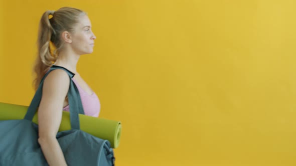 Slow Motion of Young Woman Carrying Sports Bag with Yoga Mat and Water Bottle Walking
