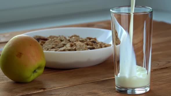 Pouring Milk Into a Glass for Breakfast with Oatmeal in Slow Mo