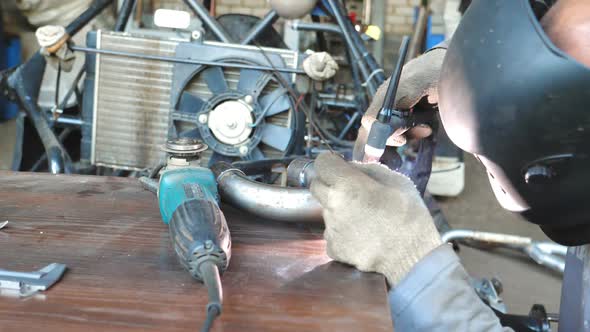 Mechanic with Protective Mask Welding Automobile Details. Repairer Fixing Auto. Man Working in