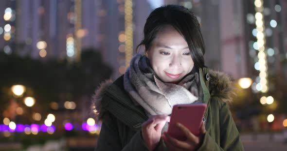 Woman use of smart phone at outdoor in winter time at night