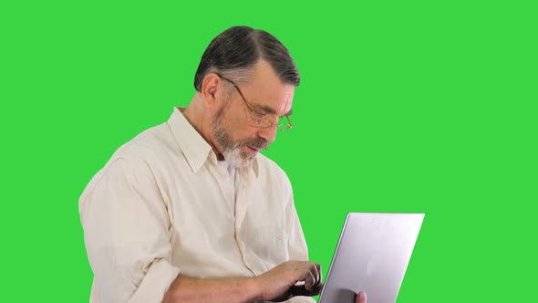 Excited Senior Business Man Working on a Laptop on a Green Screen, Chroma Key.