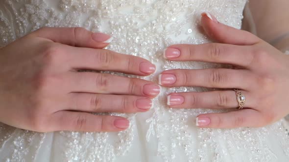 Hands of a Bride Closeup Lie on a White Wedding Dress