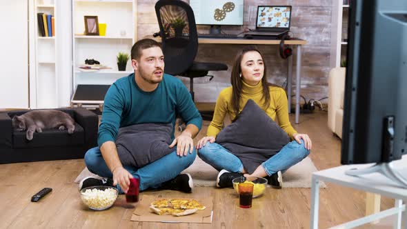 Young Couple Sitting on the Floor Cheering Up