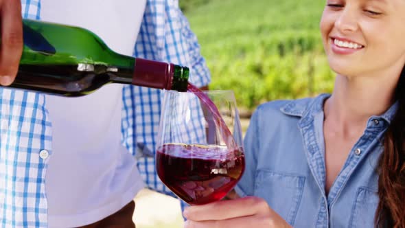 Man serving red wine to woman in the farm