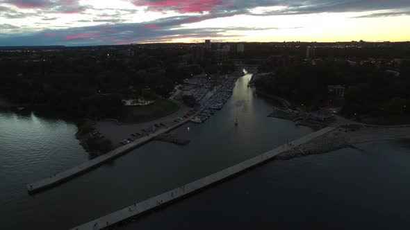 Drone descending while filming docks with tiny people walking after sunset