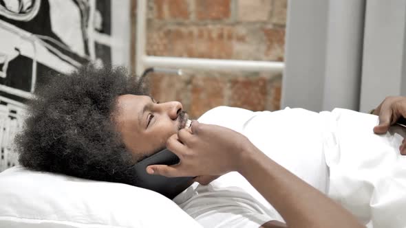 African Man Talking on Phone Lying in Bed