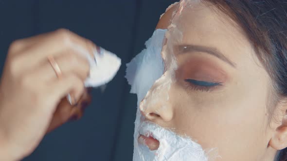 Close up of make up artist putting the white material on the woman's face and making zombie mask