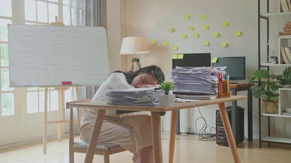 Tired Asian Woman Sleeping Due To Working Hard With Documents At The Office