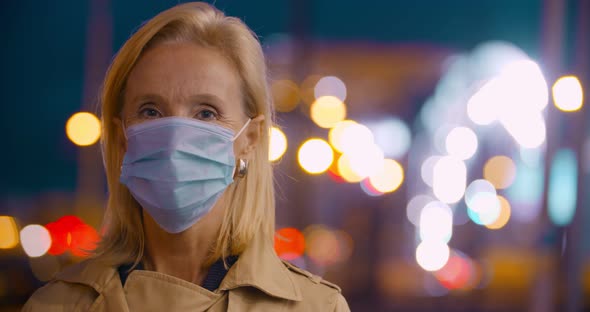 Bokeh Shot of Mature Woman with Surgical Mask in Evening City