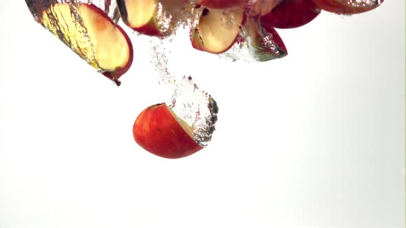 Super Slow Motion a Bunch of Apple Pieces Falls Under the Water with Air Bubbles