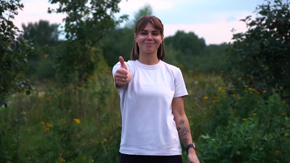 Young Nice Girl in Nature in White T-shirt Shows Thumbs Up Gesture in Slow Motion