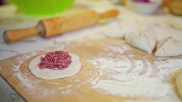 Female Hands Put Raw Meat Into the Dough Making Meat Pies