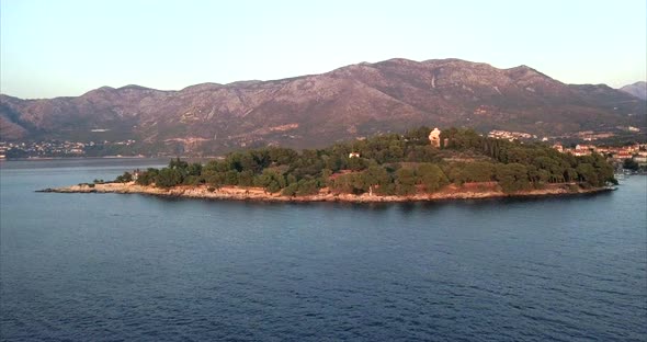 Rising aerial shot of Croatian coast during sunset with red glow from the setting sun