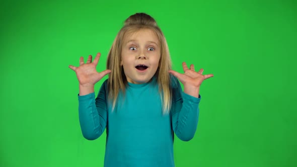 Funny Child Posing Shows Frightened Emotion on Green Background. 