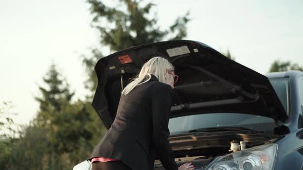 Baffled Blonde Comes Looks Under Hood of Broken Car and Confusedly Looks Around