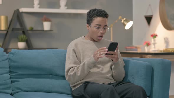 African Woman Having Loss on Smartphone at Home