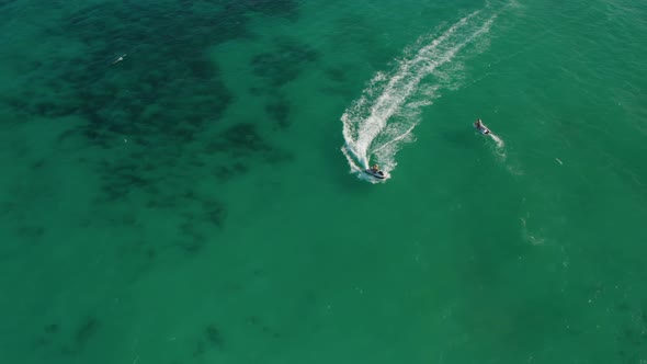 Young Couple Jetskiing at High Speed on the Green Caribbean Sea