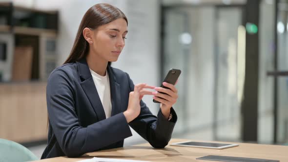 Serious Businesswoman Using Smartphone in Office