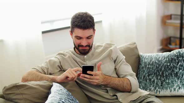 Happy Man with Smartphone at Home