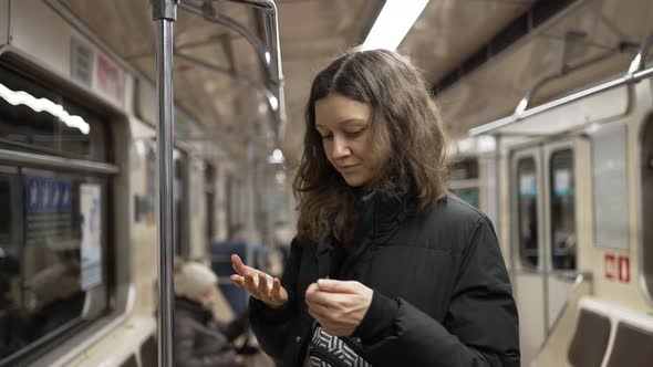 Young Woman Uses Sanitizer After Holding Handrail in Subway