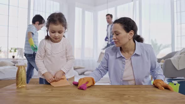 Loving Mom Teaching Daughter to Dust Off at Home