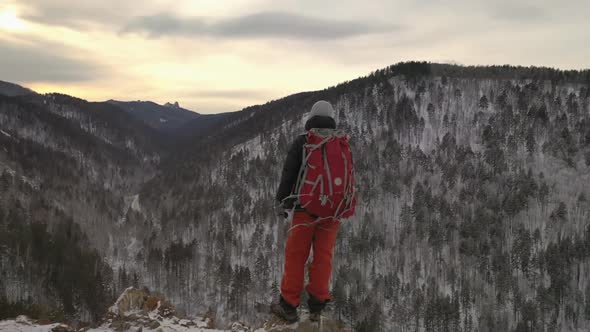 A Lone Young Male Hiker Stands on Top of a Mountain at Sunset.