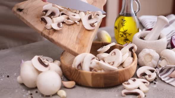 Pouring Sliced and Chopped Champignon Mushrooms Into Wooden Bowl