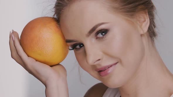 Fresh Female Face with Juicy Orange Laughing and Looking To the Camera