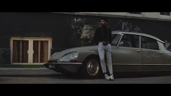 Man with a analogue camera standing next to a vintage car