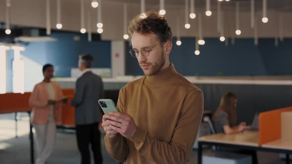 Portrait of Caucasian Businessman in Glasses Looking at the Camera After Using His Smartphone