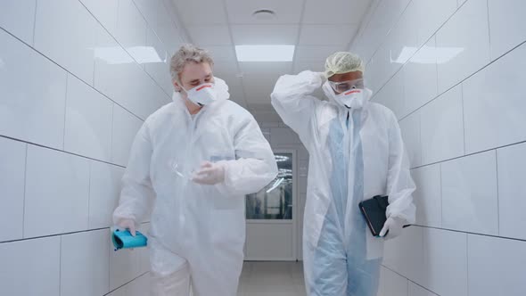 Medics Take Off Protective Suits and Masks While Walking in White Hospital Hall