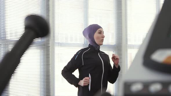 Athlete Girl in Hijab on a Running Simulator Slow Mo