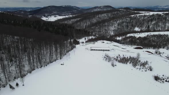 Aerial shot of snow covered valley in hills. Panoramic view with sky and clouds.