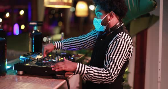 Black Dj playing music at cocktail bar outdoor while wearing face safety mask