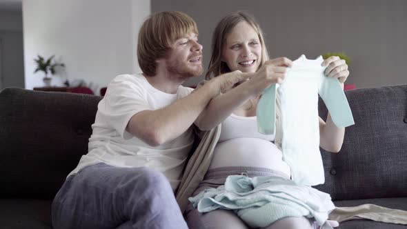 Happy Young Couple Looking at Clothes for Boy