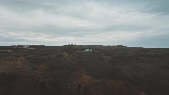 Drone shot zooming out to coastal landscape featuring two man and a van