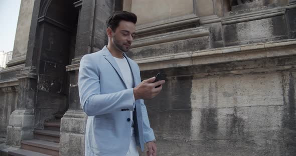 Young Man Reads An SMS On The Phone While Walking Around The City