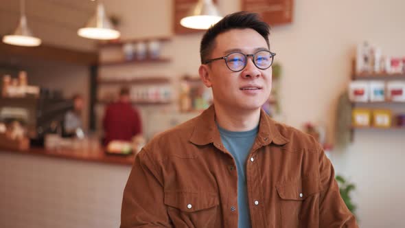 Cheerful Asian young man wearing eyeglasses looking at the camera