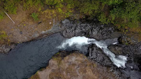 Aerial overhead footage of river flowing through rocky terrain in the forest.