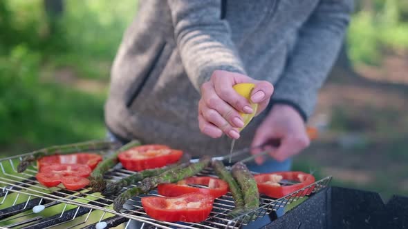 Making Grilled Vegetables  Adding Lomon Juice to Asparagus and Red Pepper on a Charcoal Grill