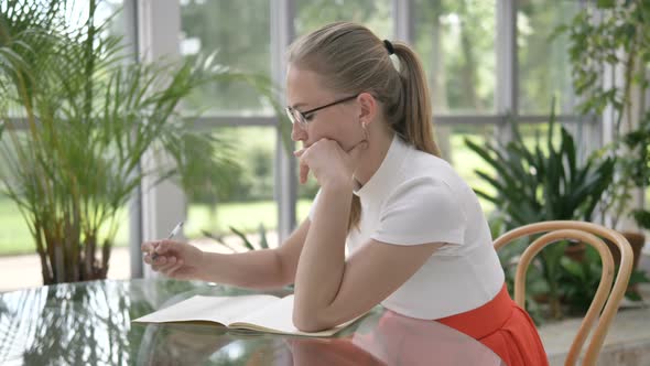 Elegant Businesswoman Writes in Notebook Sitting at Table