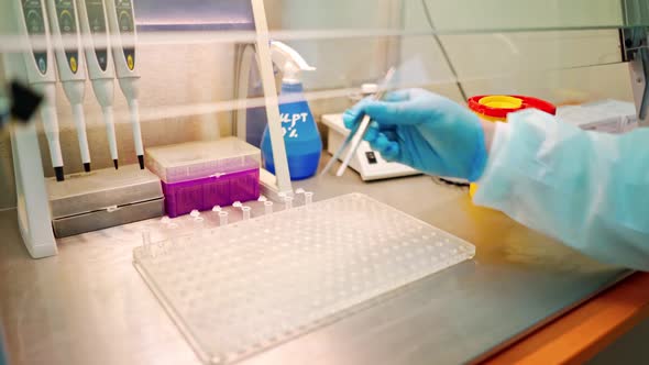 Hand of laboratory worker with tweezers on the table