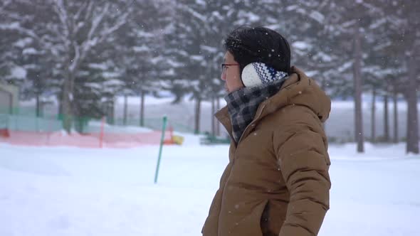 Asian Man In Winter Clothes Standing Under Snow Fall